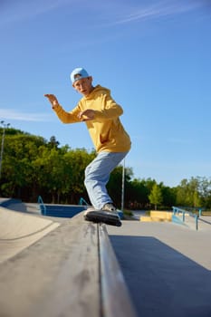 Talented teen guy roller skating making trick on border. Extreme sports competition outdoors