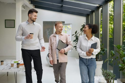 Diverse interracial colleague team talking discussing received new information going to office workstation after coffee break or business meeting and conference room. Friendly conversation