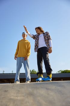 Two teenager sportsman discussing future free riding race on roller skates. Extreme sport and outdoor skate park activity
