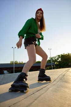 Active teenager girl rollerskater riding at outdoor rollerdrom. Summer recreational activity