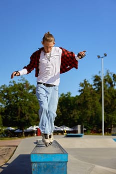 Teenager rollerskater balancing on pedestal performing extremely ride tricks. Recreation activity at skating park at summer day