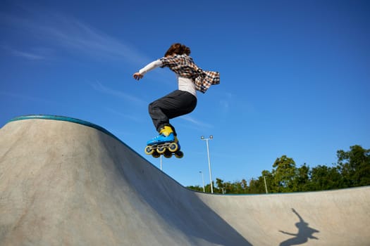 Teenager guy riding roller skates performing speed moving. Teen boy improving physical shape and skills