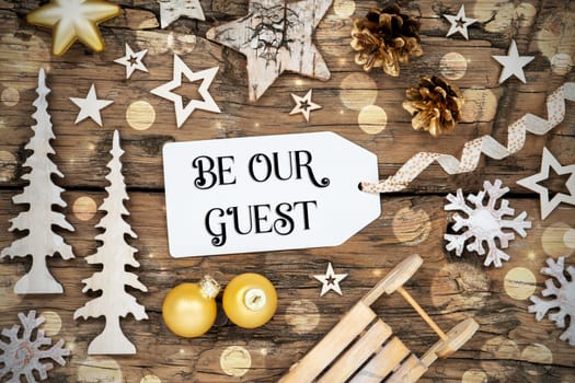 Rustic Wooden Bokeh Christmas Background, Winter Decoration With Label With Text Be Our Guest