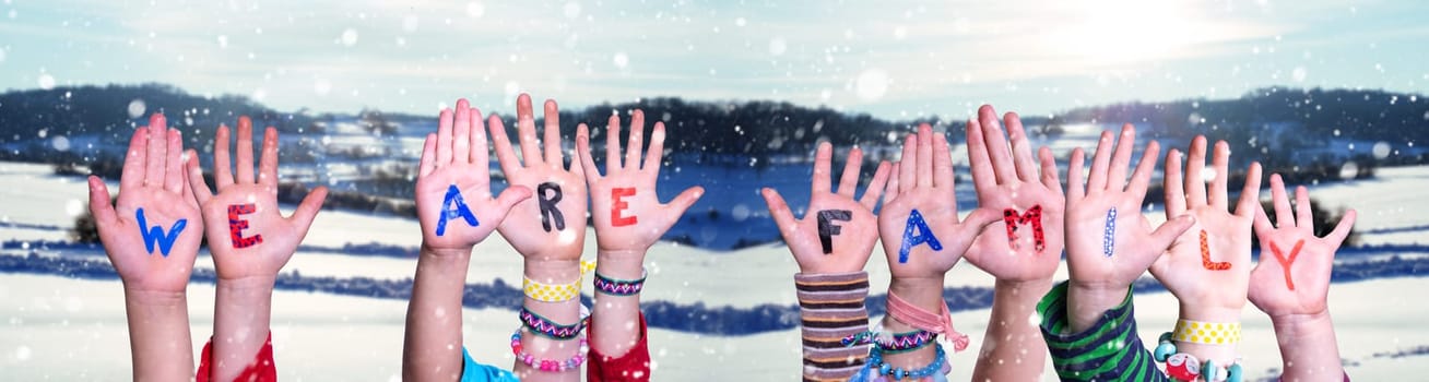 Children Hands Building Colorful English Word We Are Family. White Winter Background With Snowflakes And Snowy Landscape.