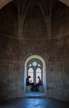 Beja, Portugal - Jul 27th, 2023: Visitors sitting beside interior window bench of the fortress. Beja Castle, Baixo Alentejo, Portugal