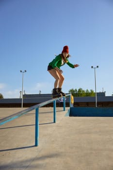 Talented teenager girl riding on handrail practicing extreme tricks. Dangerous roller skating stunt