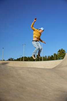 Skilled teenager boy wearing casual clothing and in roller blades jumping on ramp. Inline skates sport
