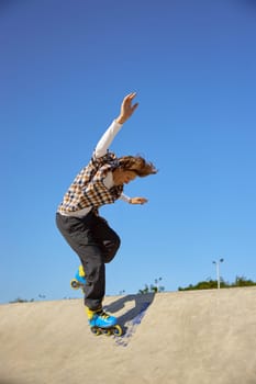 Young boy in rollerblades making stunt on cement ramp in skate park. Urban extreme sport recreation for teens