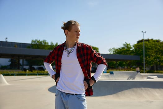 Portrait of fashioned teenager sportsman looking aside over rollerdrom. Urban area for rollerblading