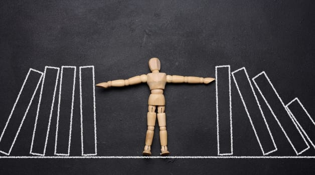Wooden puppet toy holding a falling domino, representing the concept of a strong personality