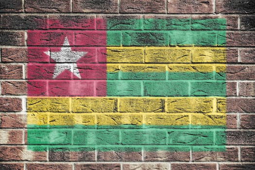 Togo flag on a brick wall background green red yellow stripe white star