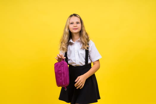 Little teenager girl with pencil case on a yellow background
