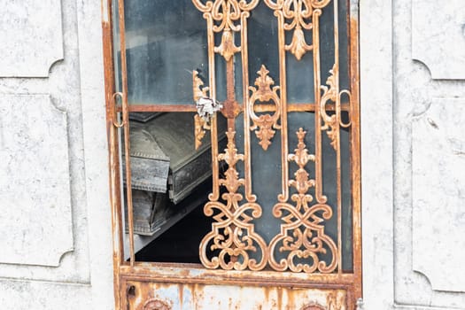 February 22, 2023 Lisbon, Portugal: Alto de Sao Joao Cemetery - a broken window and a grave inside the crypt. Mid shot