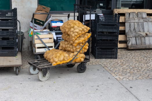 Sacks of potatoes on the street by other containers. Mid shot