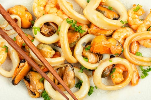 Roasted mussels, squid and shrimp and chopsticks, close up.