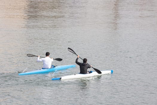 Two guys rowing in a canoe at marina. Mid shot
