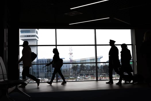 Silhouettes of busy people walking at the airport. Mid shot