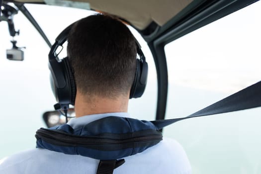 The back of the head of a helicopter pilot with headphones. Mid shot