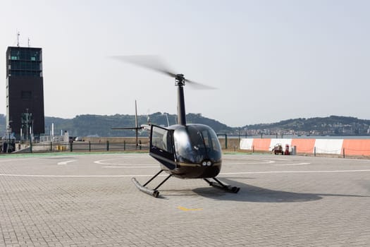 Black helicopter parked on the landing pad. Mid shot