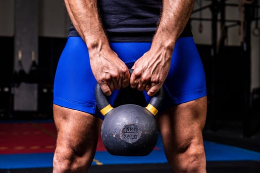 Closeup of man holding heavy kettlebell at the gym.