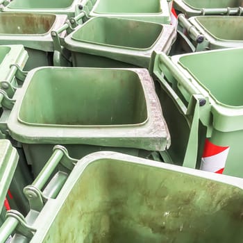 Row of empty green rubbish bins on the street.