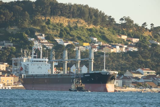 11 April 2023 Lisbon, Portugal: a large cargo ship and a small boat nearby. Mid shot