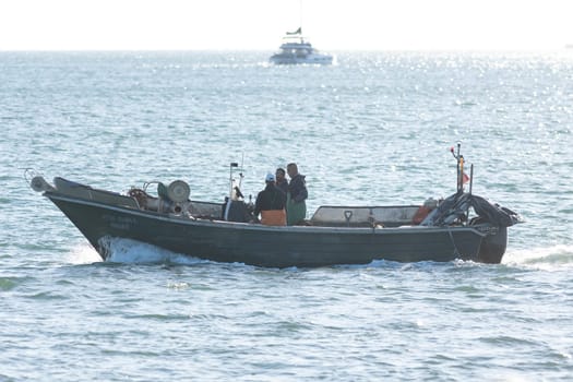 11 April 2023 Lisbon, Portugal: workers on a motorboat swim on tagus river. Mid shot