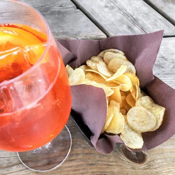 Spritz Aperol with chips, for a perfect pre-dinner. Classic Italian aperitif.
