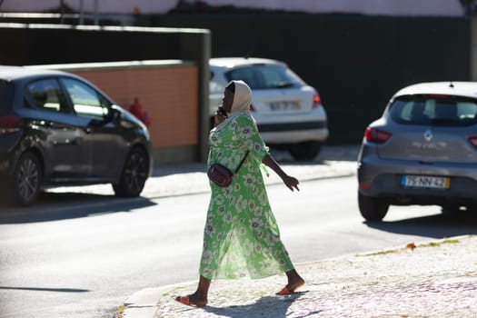 11 April 2023 Lisbon, Portugal: black woman walking on street talking on her phone. Mid shot