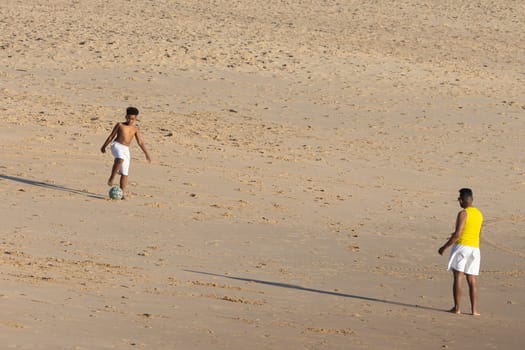 19 April 2023 Lisbon, Portugal: Costa da Caparica - black kids playing with a ball on the beach. Mid shot