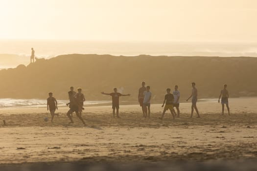 19 April 2023 Lisbon, Portugal: Costa da Caparica - young men playing soccer on the beach. Mid shot