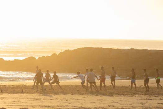 19 April 2023 Lisbon, Portugal: Costa da Caparica - young men playing soccer on the beach at sunset. Mid shot
