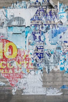 Concrete wall with colorful ripped bill posters. Grunge background