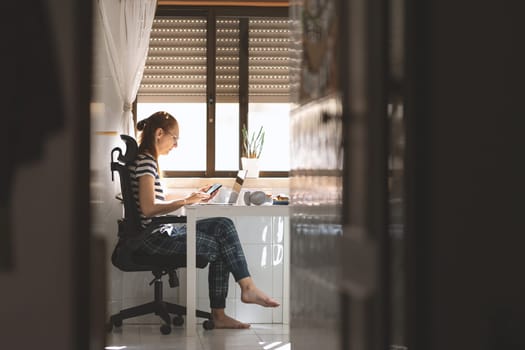 An adult woman working at the kitchen table. Mid shot