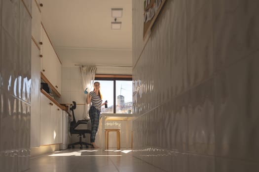 Adult housewife woman standing in the kitchen with a rag to wipe the windows. Mid shot