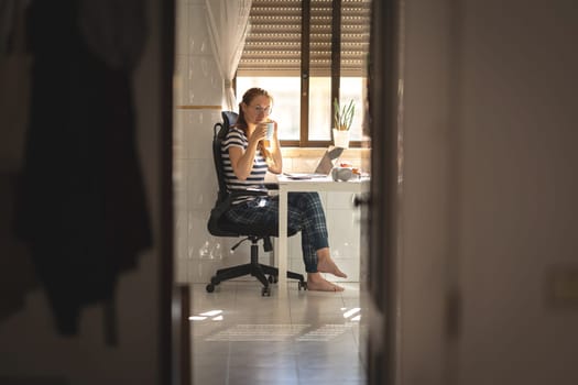 Adult woman with a cup of coffee at the kitchen table - looking in the camera. Mid shot