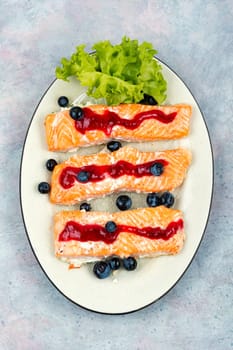 Baked salmon fish with blueberry berry sauce. Salmon fillets, grilled steaks on a wooden table. Top view.
