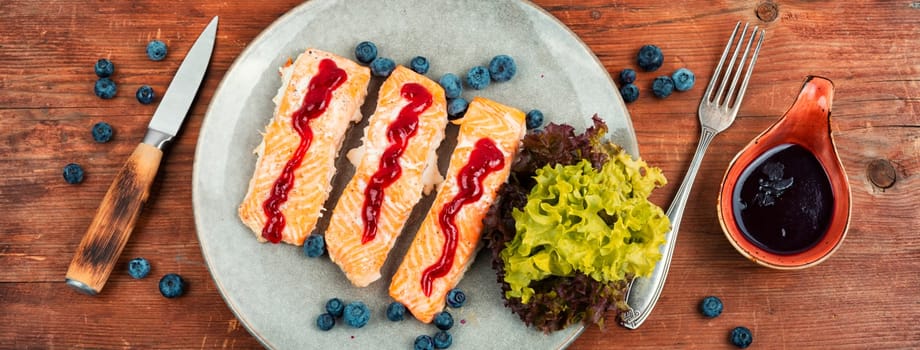 Baked salmon fish with blueberry berry sauce. Salmon fillets, grilled steaks on a wooden table. Top view.