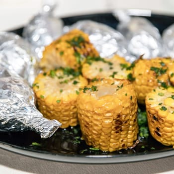 Grilled corn on the cob with green parsley. Tasty dish.