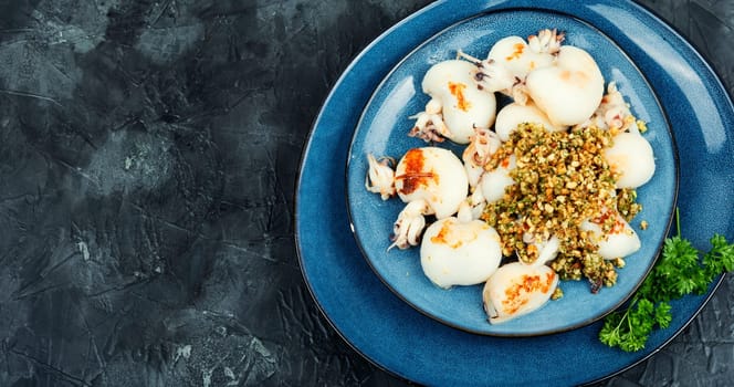 Baked young squids or calamari with nut garnish. BBQ.