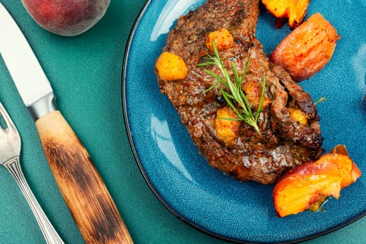Tasty beef steak with peach in fruit marinade. Close-up.