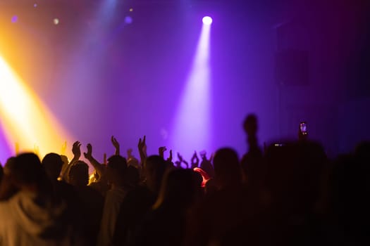 The crowd stretches their hands up at the concert. Mid shot