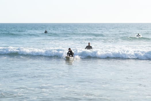 A family of surfers - father teaching his son how to serf. Mid shot
