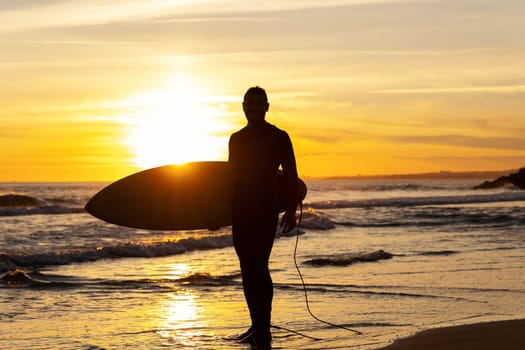 Silhouette of an athletic man surfer on the seashore. Mid shot
