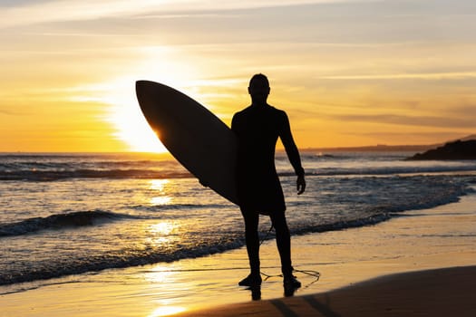 Silhouette of a fit man surfer on the seashore. Mid shot