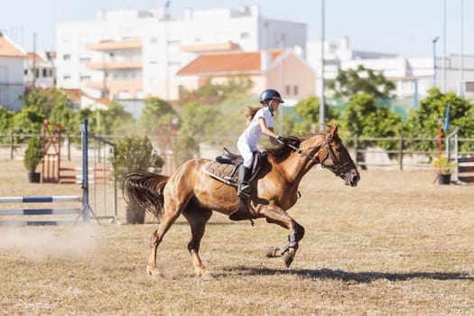 30 april 2023 Sobreda, Portugal: Festival Hipico da Sobreda - a little girl riding a light brown horse at ranch. Mid shot