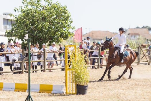 30 april 2023 Sobreda, Portugal: Festival Hipico da Sobreda - a girl riding a brown horse at ranch. Mid shot