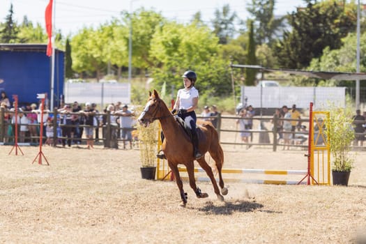 30 april 2023 Sobreda, Portugal: Festival Hipico da Sobreda - a girl riding a brown horse at the ranch. Mid shot