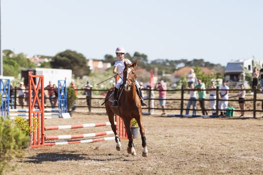 30 april 2023 Sobreda, Portugal: Festival Hipico da Sobreda - a little girl riding a horse at ranch. Mid shot