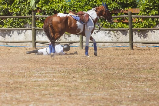 A kid falling from a horse at the ranch. Mid shot